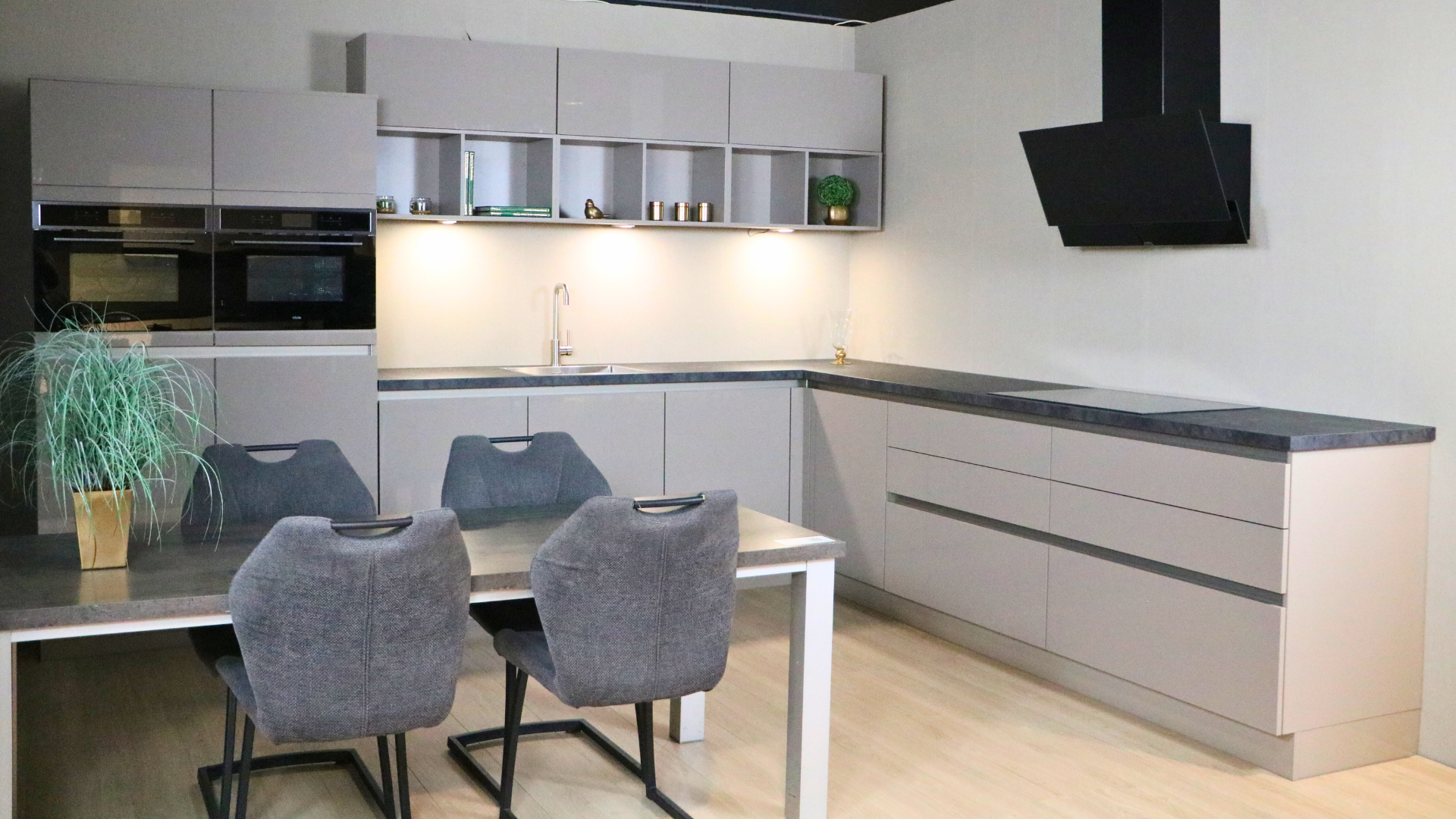 Een greige hoogglans hoekkeuken met handige vouwklep bovenkasten voor extra opbergruimte in de showrooms van Keukenwarenhuis.nl in Dordrecht en Ter Aar