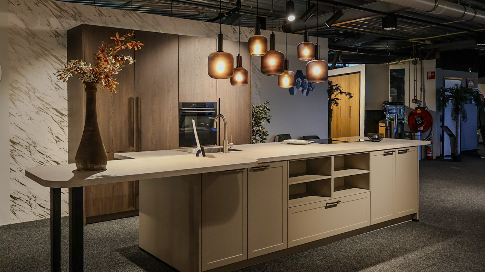 Taupe eilandkeuken gecombineerd met een houtlook kastenwand in de showroom van Keukenwarenhuis.nl in Ter Aar